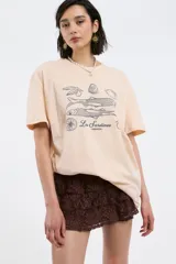 Remera color beige con estampado de sardinas, limones y aceitunas.