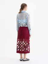 Pollera cruzada de largo midi, confeccionada en guipur negro con espejos circulares bordados. Presenta un lazo de ajuste en la cintura y forrería interna al tono.