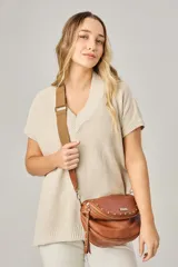 Bandolera de cuero celeste con correa de cinta regulable, forro de algodón, cierre central y bolsillo trasero con cierre.