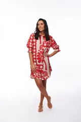 Vestido corto tipo camisero con botones al frente y mangas cortas con elástico y volado. Estampado con flores rojas y beige.