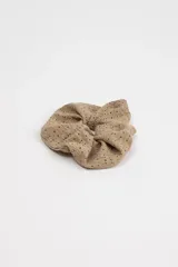 Scrunchie beige con textura perforada.
