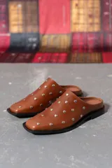 Zueco marrón de cuero con tachas plateadas.