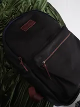 Mochila negra de cuero con forro de lino y cierres de bronce. Tiene un compartimento interno para computadora.