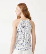 Musculosa blanca con estampado de peces azules, cuello halter con detalle de cuerda y sisa americana.