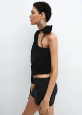 Blusa negra de terciopelo con estampado floral, diseño asimétrico de un solo hombro, manga larga abullonada y detalle de flor en el cuello.