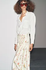 Falda midi de tiro medio confeccionada en hilatura de algodón. Tejido con tablas y estampado floral. Bajo acabado en vivo a contraste. Cierre lateral con cremallera oculta en costura.