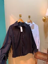 Camisa negra de manga larga con flecos en las mangas y cierre con botones.
