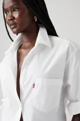 Camisa blanca de corte boyfriend, manga larga y bolsillo en el pecho con logo de la marca.