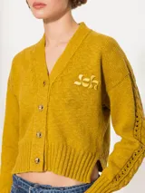Cardigan corto color mostaza, tejido en hilado de lino combinado con algodón grueso. Incluye bordado a tono Jch.