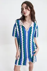 Vestido corto tejido de punto con cuello tipo camisa, botones frontales y diseño a rayas onduladas en tonos azul, verde y blanco.