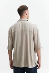 Camisa negra oversize de manga corta con cuello clásico y bolsillo en el pecho.