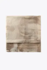 Pañuelo rectangular color beige con estampado abstracto en tonos marrones. Tiene acabado deshilachado en los bordes.