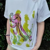 Remera blanca de algodón con estampado serigrafiado a mano de un pulpo en tonos rosados, morados y verdes.