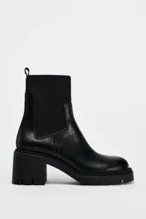 Botín Chelsea negro de cuero con caña de neopreno, tacón bloque y suela track.