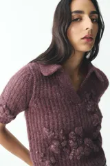 Jersey de punto color borgoña con cuello solapa y escote en pico. Tiene mangas cortas y bordados florales a tono.