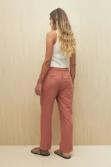 Pantalón beige de tiro medio con cintura elastizada y cordón regulable, bolsillos laterales y calce relajado.