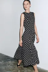 Vestido midi negro con estampado de lunares blancos, cuello redondo y sin mangas.