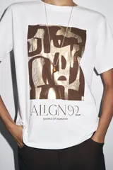 Camiseta blanca de algodón con cuello redondo, manga corta y estampado metalizado en el frente con formas abstractas y texto "AILGN92 SHAPES OF HARMONY".