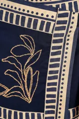 Minifalda azul marino con estampado floral dorado, corte asimétrico y lazo lateral.