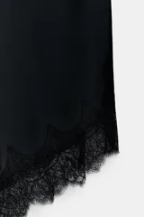 Falda midi de satén color negro, de corte al bies y terminación asimétrica con encaje.