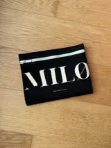 Clutch o neceser negro de neopreno con cierre de cremallera blanco y logo grande en blanco con tipografía serif.