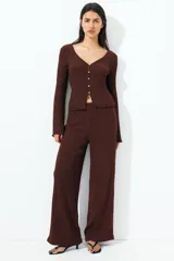 Pantalón marrón de punto con textura arrugada, corte holgado, tiro alto, cintura elástica y piernas rectas.