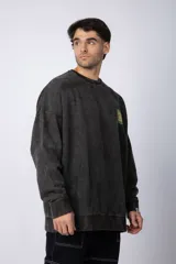 Buzo de cuello redondo y corte oversize en tela friza, color gris con efecto acid wash. Presenta un estampado frontal en color verde lima con un diseño abstracto.