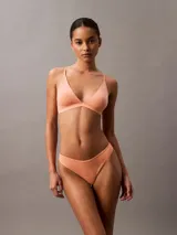 Conjunto Calvin Klein de algodón color durazno, compuesto por un corpiño triangular de breteles finos y una colaless de tiro bajo.