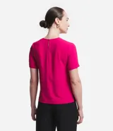 Blusa blanca de poliéster con cuello redondo, mangas cortas, cierre trasero en forma de gota, pequeñas aberturas laterales y acabados en pespuntes en las mangas y el cuello.