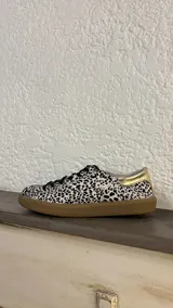 Zapatillas bajas de cuero negro con cordones y suela de goma color caramelo.
