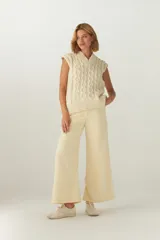 Chaleco de punto color crema con diseño trenzado y cuello en V.