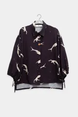 Camisa negra con estampado de sirenas blancas, cuello clásico, cierre con botones y mangas 3/4 abullonadas con lazos en los puños.