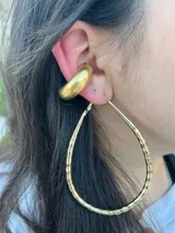 Set de dos aros dorados, uno tipo cuff grueso y otro tipo argolla con textura.