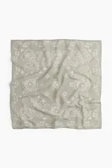 Pañuelo cuadrado gris con estampado de flores y arabescos en blanco.