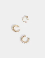 Set de tres earcuffs dorados: uno liso con textura, uno con detalle de corazón y uno con perlas.