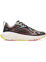 Championes Under Armour Aura RPSTP, con capellada de color marrón y detalles en negro, gris y amarillo. Presenta el logo de Under Armour en el lateral y una suela gruesa de color blanco con detalles en amarillo y rojo.