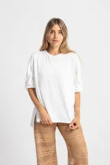 Remerón blanco de algodón, con mangas 3/4 con pliegues y elástico en el puño, y aberturas laterales en el ruedo.
