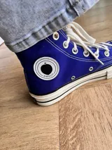 Zapatillas de lona blancas de caña alta con cordones y puntera de goma. Logo de durazno engomado en la base y en la cara interna.