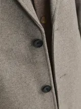 Tapado gris con cuello tipo spread y cierre de botones. Confeccionado en tejido mezcla de poliéster y lana reciclada.