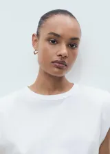 Camiseta blanca de manga corta con hombreras y cuello redondo, de corte recto.