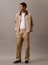 Pantalón cargo color beige de algodón orgánico elástico, con cintura elástica y corte recto. Presenta bolsillos laterales, traseros y tipo cargo en las piernas.