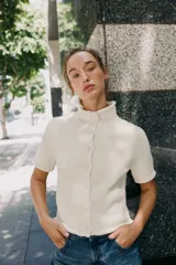 Chaqueta azul marino de punto con cuello subido y manga corta. Cierre frontal con botones.