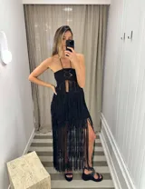 Falda larga negra de algodón con diseño de flecos largos que caen desde el busto, estilo vestido. El corpiño es tipo bandeau con detalle de tejido calado y abertura frontal.