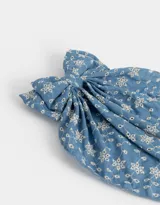 Hebilla francesa para el pelo con moño grande de tela celeste con bordado de flores blancas.