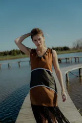 Vestido corto marrón con detalles en negro y flecos en el ruedo. Confeccionado artesanalmente con diferentes cueros bordados a mano y espalda en tejido de hilado.