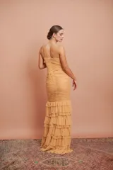 Vestido largo color durazno, entallado, con escote en V, breteles finos, drapeado en el frente y falda con volados.