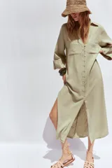 Vestido camisero largo color verde claro, confeccionado en lino. Tiene cuello solapa, escote en V, manga tres cuartos con trabilla y botón, bolsillos delanteros de plastrón, aberturas laterales en el ruedo y cierre frontal con botones.