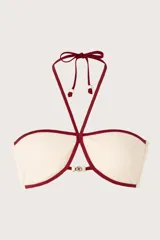 Top de bikini bandeau blanco marfil con ribete rojo oscuro. Tiene tiras que se anudan al cuello para un amarre halter, adornadas con delicados detalles de cuentas doradas.
