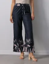 Pantalón negro con estampado de hojas color rosa en el ruedo y cintura elastizada con lazo ajustable.