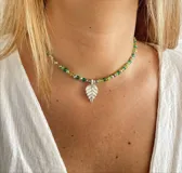 Collar con cuentas en tonos verdes y un colgante en forma de hoja.